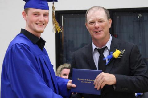 Moss school board member Bryan Smith presents diplomas