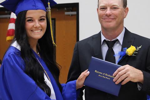 Moss school board member Bryan Smith presents diplomas