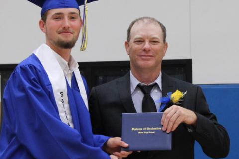 Moss school board member Bryan Smith presents diplomas