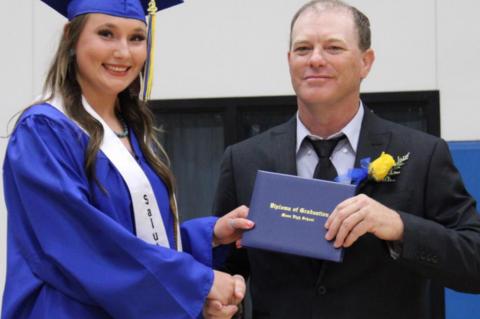 Moss school board member Bryan Smith presents diplomas